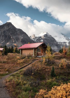 Wooden huts with Rocky mountains in autumn forest at Assiniboine provincial park, BC, Canada clipart