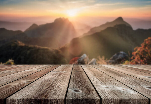 Wooden table top on blurred sunset on mountain in wildlife sanctuary at Doi Luang Chiang Dao national park background