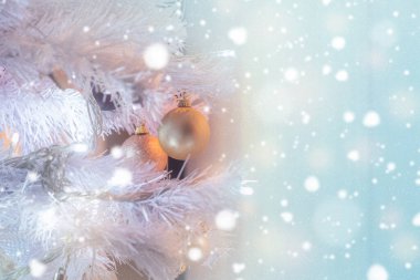 Beyaz Noel ağacı, altın topları ve arka planda ışıldayan karla