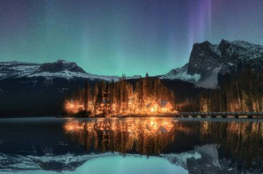 Wooden lodge illuminated with Aurora borealis on Emerald lake at Yoho national park, Canada clipart