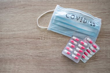 Tıbbi yüz maskesi, metin covid-19 ve ahşap masada antibiyotik. Coronavirus kavramı, Covid-19