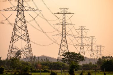 Yüksek voltaj direğinin ayarlanması, gün batımında kırsal bölgede pirinç tarlasında iletişim kulesi.