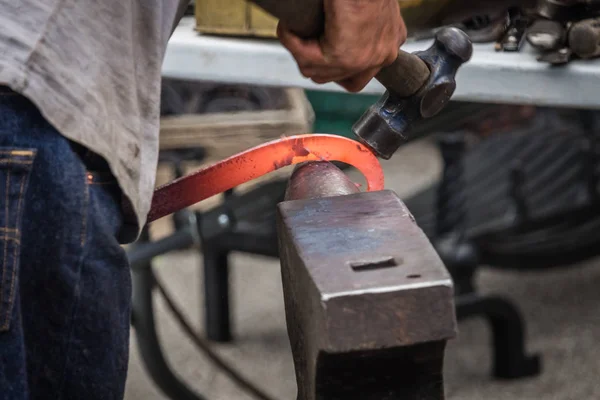 Um ferreiro martelando ferro quente — Fotografia de Stock