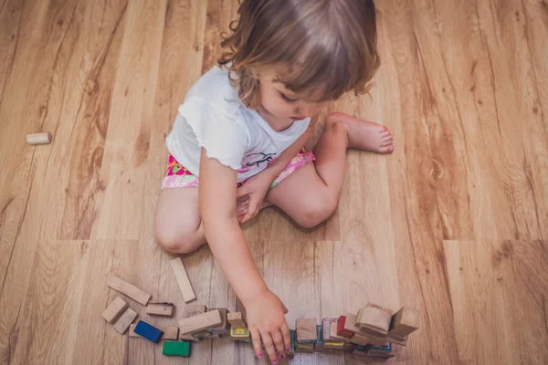 Chica jugando con bloques de construcción en el suelo —  Fotos de Stock