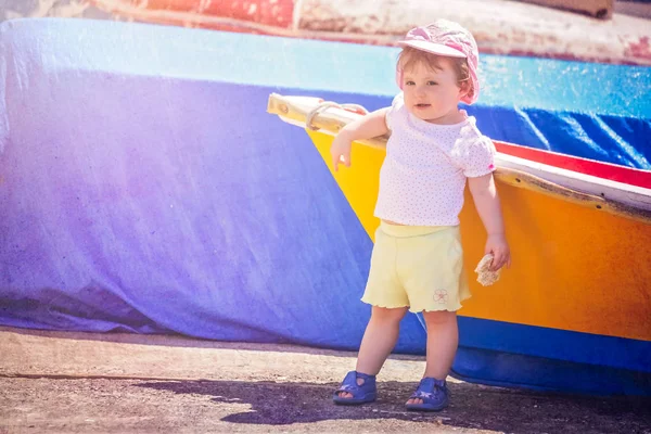 Pequena menina bonito inclinado em um barco de madeira colorido — Fotografia de Stock