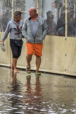 Su basmış bir kaldırımda yürüyen Çift