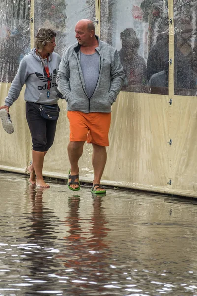 Su basmış bir kaldırımda yürüyen Çift
