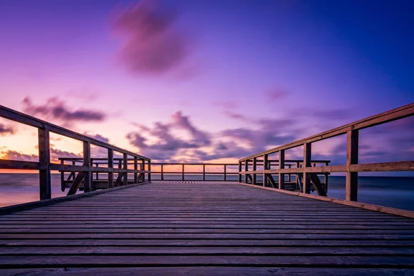 Houten pier op het strand bij zonsondergang — Stockfoto