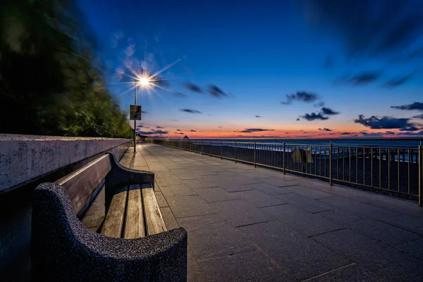 Leere Bank auf einer Strandpromenade in der Abenddämmerung — Stockfoto