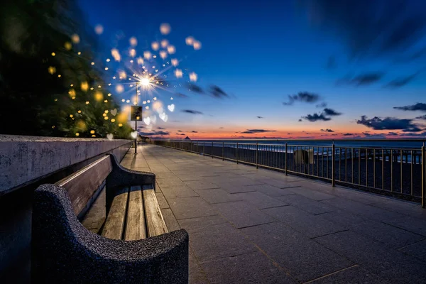 Tom bänk vid en strandpromenad i skymningen — Stockfoto