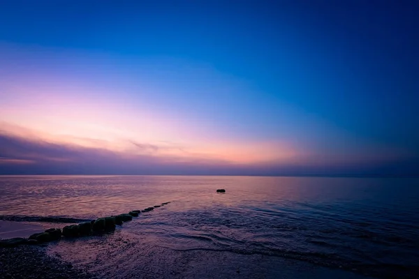 Alte hölzerne Buhnen an der Küste bei Sonnenuntergang — Stockfoto
