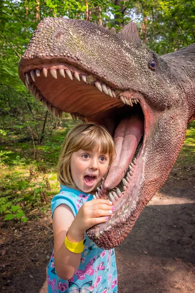 Kleine Mädchen mit dem Kopf im Mund eines Dinosauriers — Stockfoto