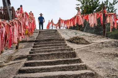 Huasha 'daki West Peak zirvesine giden taş merdivenlerde bir turist.