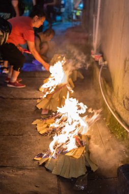 İnsanlar dini festival töreninde kağıt yakıyor.