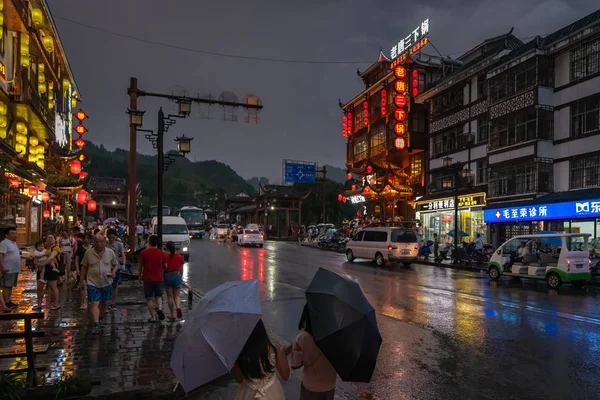 Ludzie spacerujący w deszczu w mieście Wulingyuan w nocy — Zdjęcie stockowe