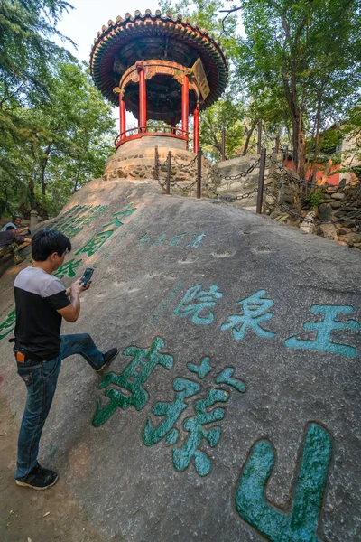 Mann malt chinesische Kalligrafie-Schriftzeichen auf einen Felsen — Stockfoto