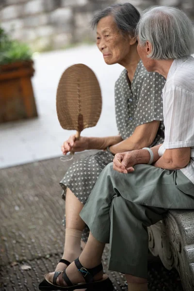 Två gamla pensionerade kinesiska asiatiska kvinnor sitter i en park — Stockfoto