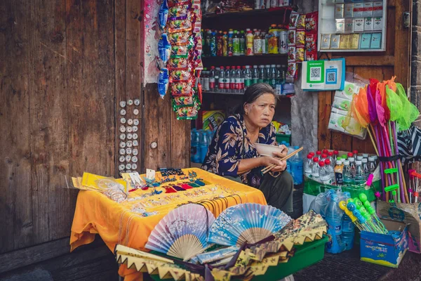 Стара китайська пані продає сувеніри. — стокове фото