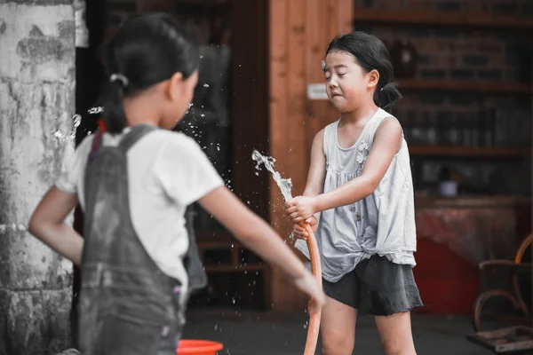 Chica china jugando con manguera de agua — Foto de Stock