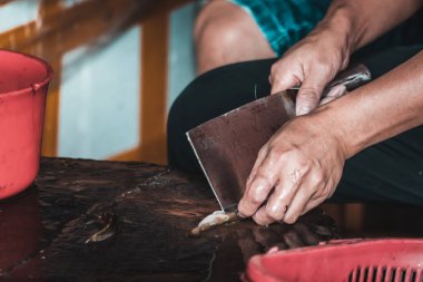 Çinli insan küçük balığın derisini yüzüyor.