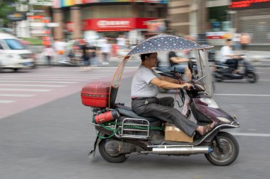 Chongqing, Çin - Ağustos 2019: Adam kalabalık bir sokakta scooterla tehlikeli bir şekilde hızlı gidiyor