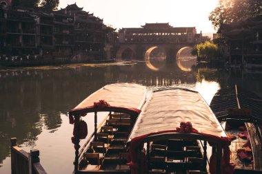 Feng Huang, Çin - Ağustos 2019: Eski tarihi ahşap turist tekneleri Tuo nehrinin kıyılarında, Fenghuang Eski Kasabası 'nın merkezinden akıyor.
