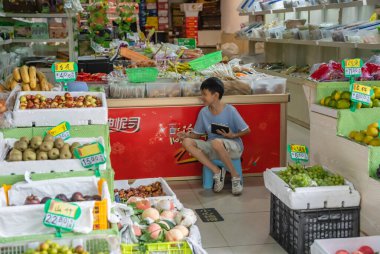 Zigong, Çin - Temmuz 2019: Genç bir çocuk annesine yardım ediyor, oturuyor ve Çin süpermarketi Zigong, Sichuan Eyaleti 'nde ürünlere bakıyor.