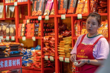 Chongqing, Çin - Ağustos 2019: Çinli kadın Chongqing kasabasındaki küçük dükkanından abur cubur satıyor