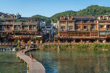 Feng Huang, Çin - Ağustos 2019: Hunan Eyaleti, Phoenix olarak bilinen Fenghuang kasabasındaki Tuo Jiang Tuojiang nehri üzerindeki ahşap köprüden geçen insanlar