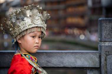 Feng Huang, Çin - Ağustos 2019: Geleneksel folklor kostümü giymiş güzel genç bir Çinli kız ve Hunan Eyaleti Fenghuang 'daki birçok köprüden birinde poz veriyor.