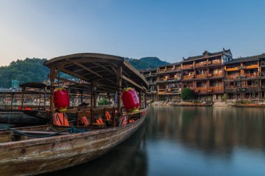 Feng Huang, Çin - Ağustos 2019: Eski tarihi ahşap turist tekneleri, Fenghuang Eski Kasabası 'nın merkezinden geçerek Tuo nehrinin kıyısına demirlediler.