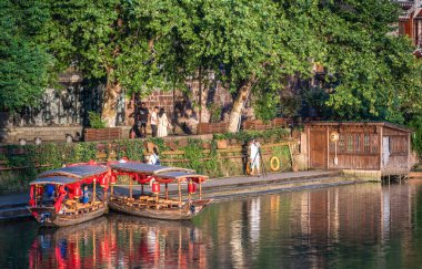 Feng Huang, Çin - Ağustos 2019: Eski tarihi ahşap turist tekneleri, Fenghuang Eski Kasabası 'nın merkezinden geçerek Tuo nehrinin kıyısına demirlediler.