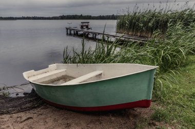 Yağışlı akşamlar Masuria gölde. Balıkçı tekne ve köprü ba