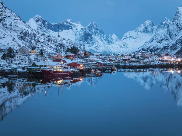 Reine 'de güzel bir şafak, Lofoten. Soğuk fiyort suyuna yansıyan uzak karlı dağlar. Limanda kalan balıkçı tekneleri