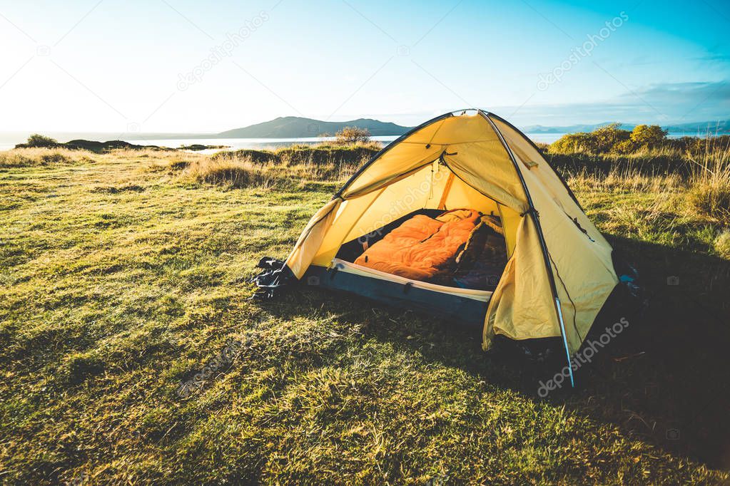 tent on camping ground in nature with sunset on background