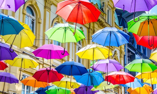 Parapluies colorés suspendus dans le ciel au-dessus du café en face du bâtiment historique — Photo