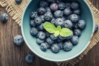 Eski ahşap masa üstü üzerinde mavi bir kabın içinde mavi çilek görüntülemek.