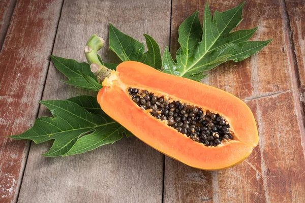 Ripe papaya with green leaf on wooden table. — Stock Photo, Image