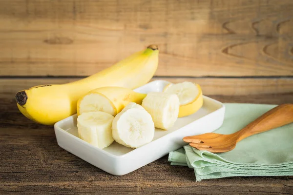 Geschnittene Banane auf weißem Teller auf altem Holztisch. — Stockfoto
