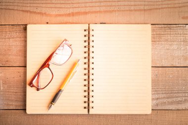 Ahşap arka plan üzerine açık defter kalem gözlüklü Üstten Görünüm