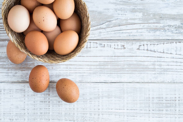 Eggs in a basket on a white wooden floor.