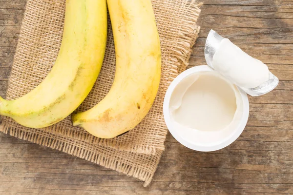 Taza de yogur y plátano sobre fondo de madera —  Fotos de Stock