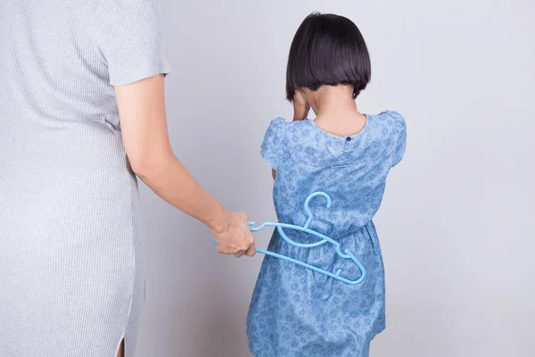 Mãe está punindo a filha batendo com um cabide — Fotografia de Stock