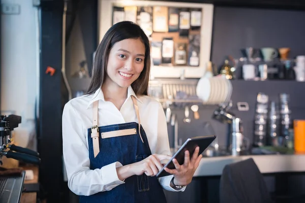 Asyalı kadın barista onun elinde tablet ile gülümseyen