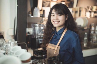 Genç Asya kadın barista aşınma mavi gömlek, sayaç gülümseyen kafede bar