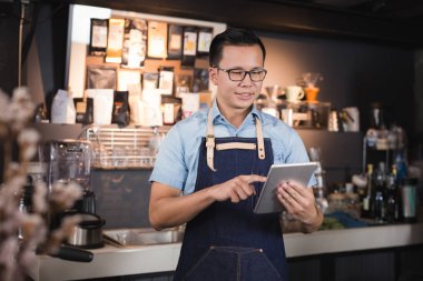 Onun elinde tablet ile gülümseyen Asya adam barista