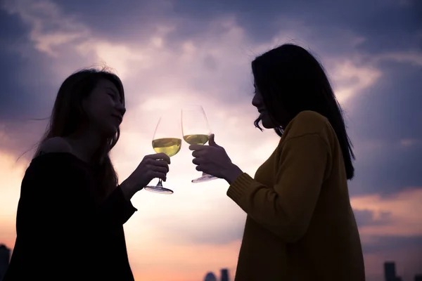 Asian woman is celebrating drinking a glass of wine together