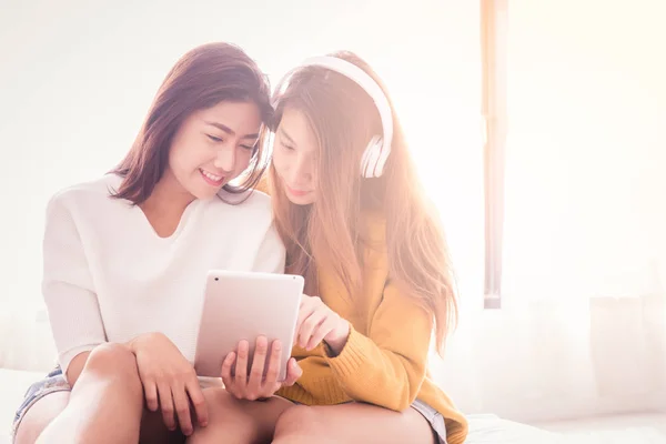 Couple of young asian women using tablet on white bed with happiness moment
