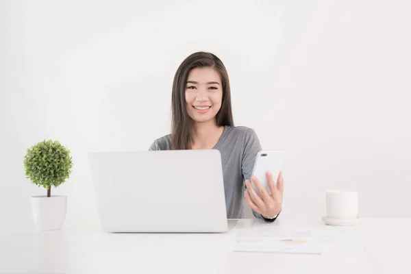 アジアの女性のオフィスの机でノート パソコンとスマート フォンを使用して — ストック写真