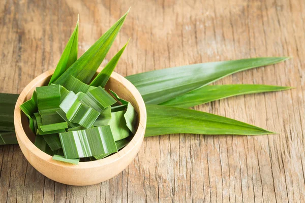 Pandan verde fresco em uma tigela de madeira na mesa de madeira, folhas de pandan no fundo de madeira velha — Fotografia de Stock